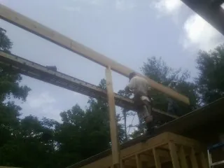 Carpenter setting a ridge beam over a new addition frame — Ice Dam Removal by Roofing Brothers in Springs