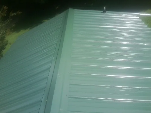 New green metal panels meeting at the ridge of a roof — Flat Roof Repair work by our crew in Springs