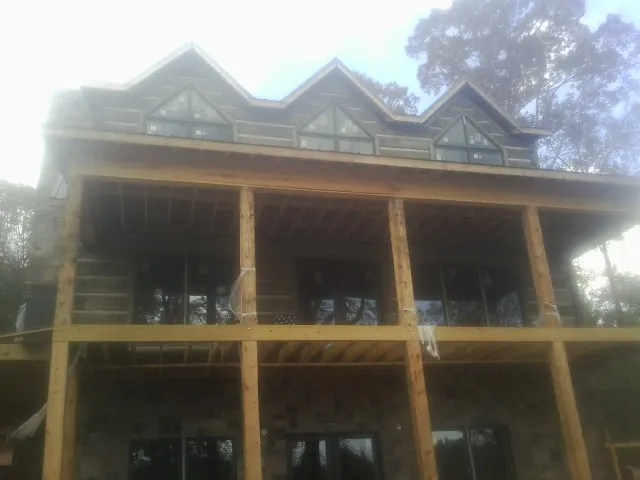 Dormers and porch framing on a large log home under construction — Roof Coating work by our crew in Springs