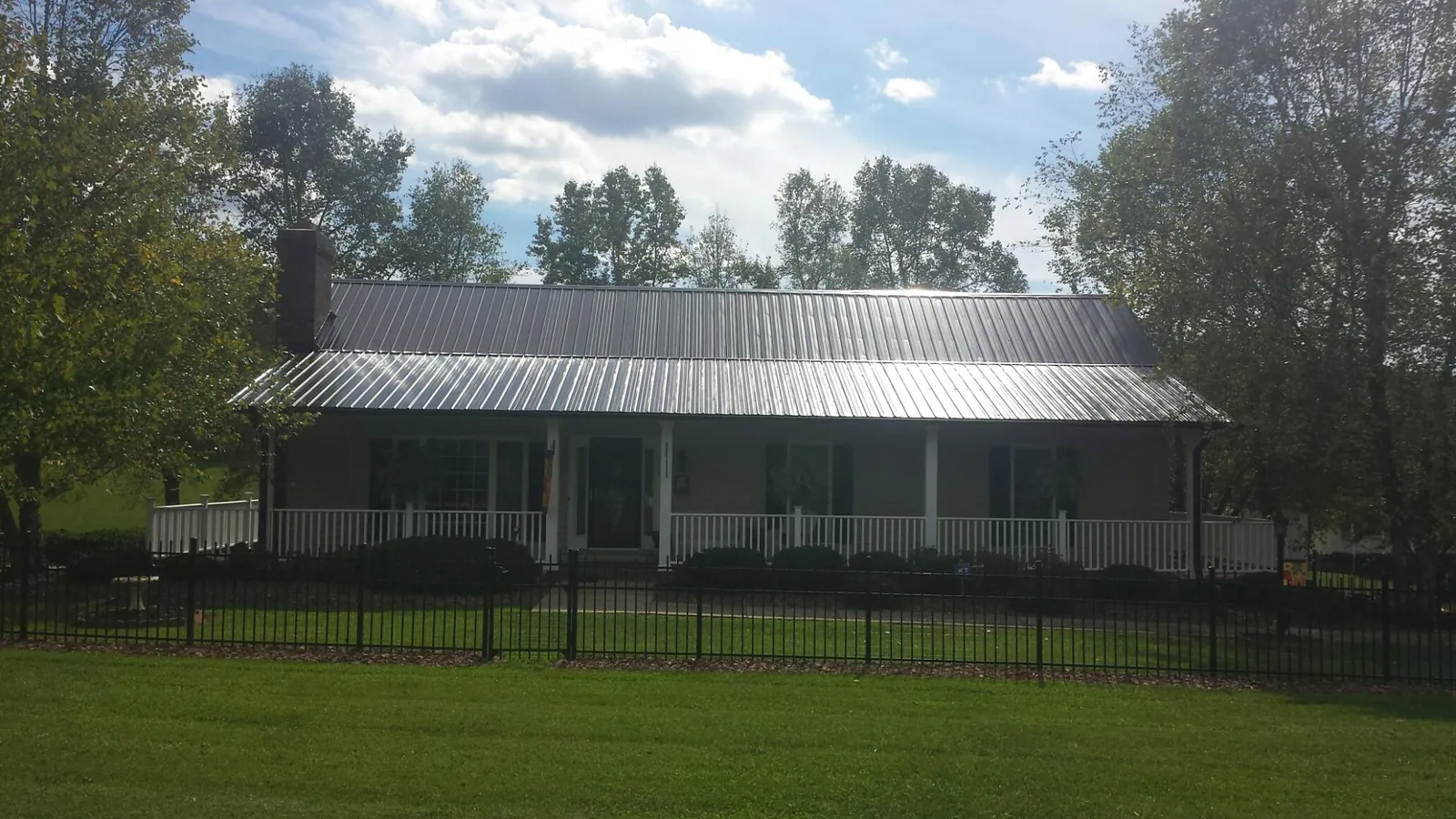 Gray metal roof on a brick ranch with a full width front porch — Gutter Guard Installation work by our crew in Springs
