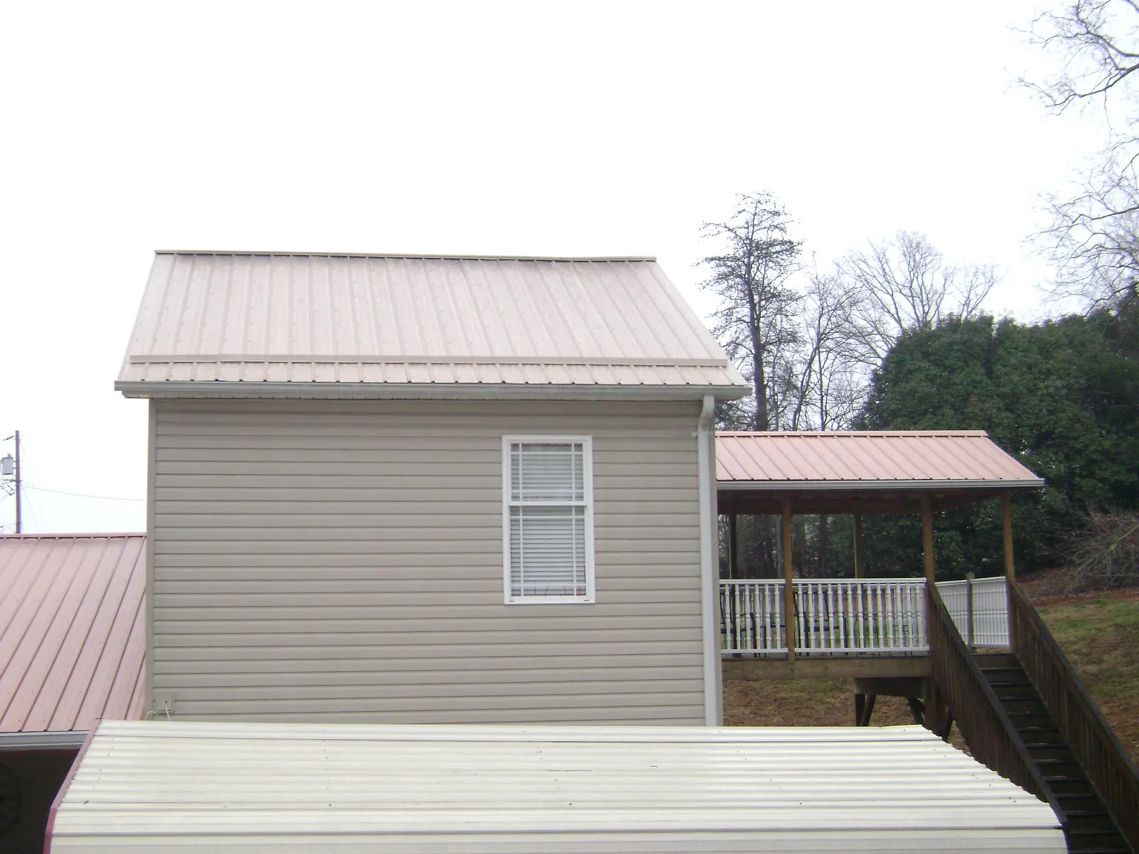 Tan metal roofs on a two story addition and attached porch, from a Roof Replacement job in Springs