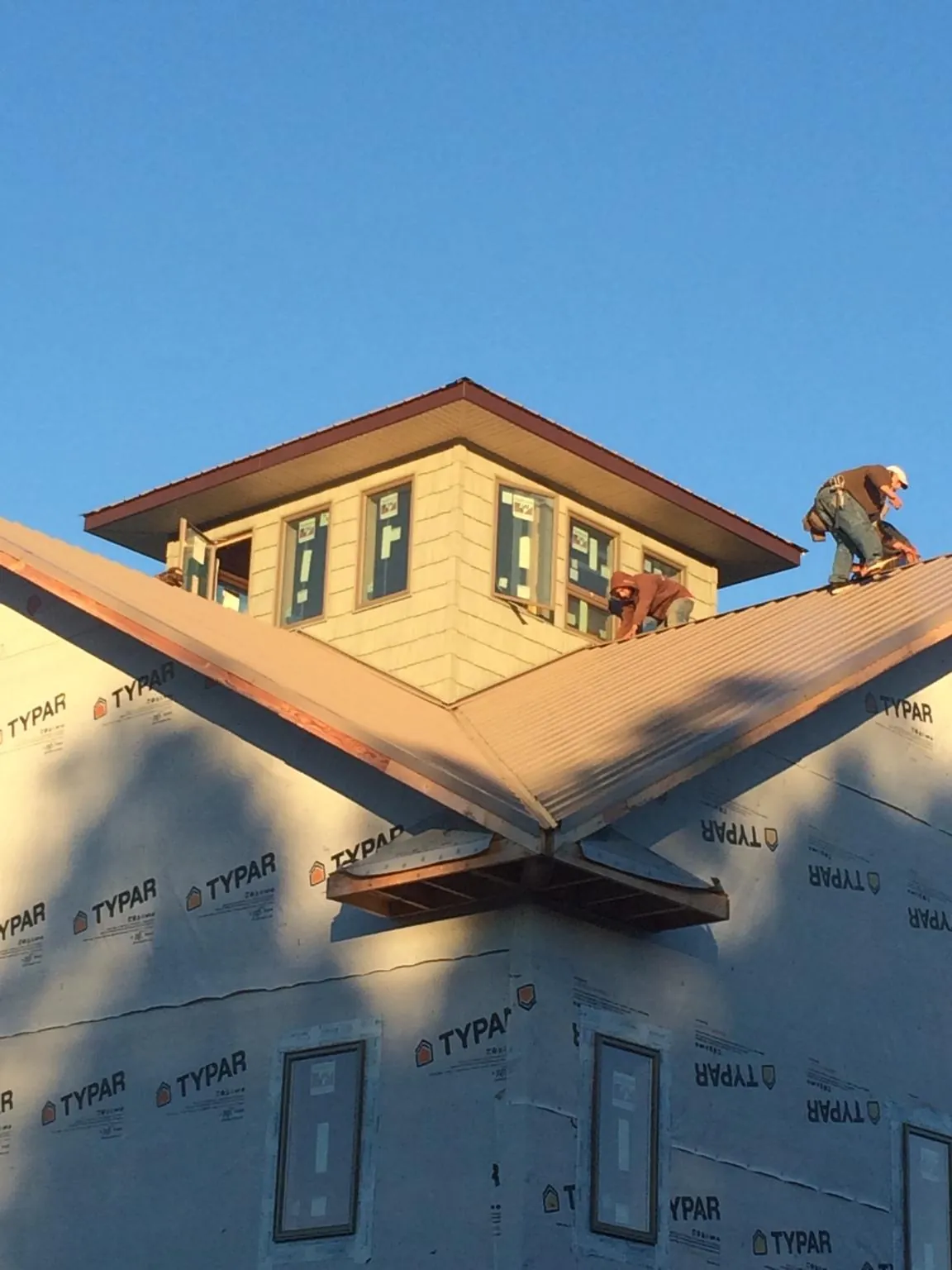 Roofers working around a rooftop cupola on a new metal roof at sunset — Roof Waterproofing in Springs by Roofing Brothers